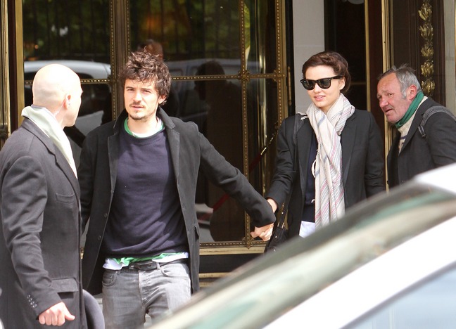 Miranda Kerr, black jacket, sunglasses, gray scarf, black purse, Orlando Bloom, black jacket, blue tshirt, green tshirt, denim jeans